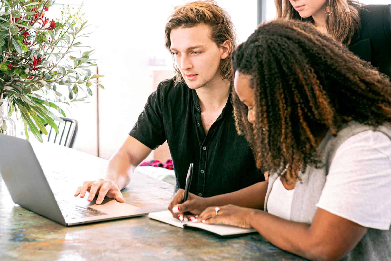 Hosting support for website design agencies. Young professionals collaborating on a project in a modern office with laptop and notes.