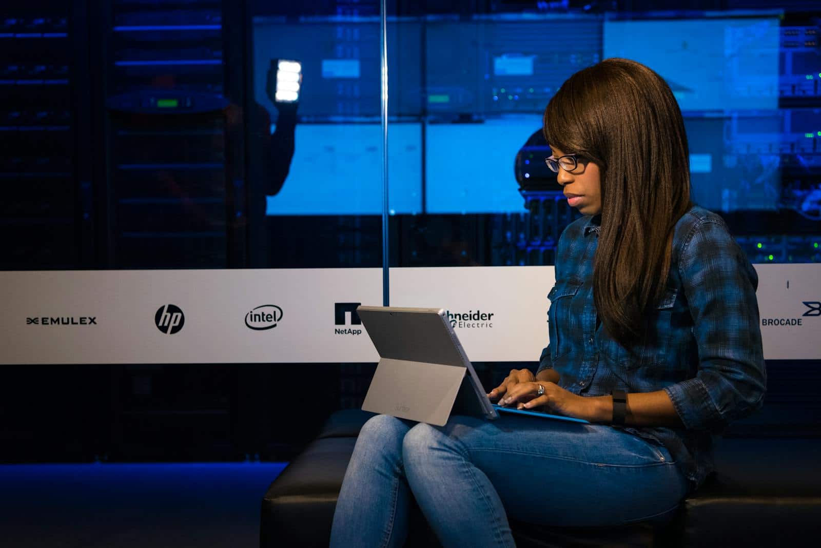 Image Compression, Professional woman working on laptop in a server room, showcasing technology and remote work.