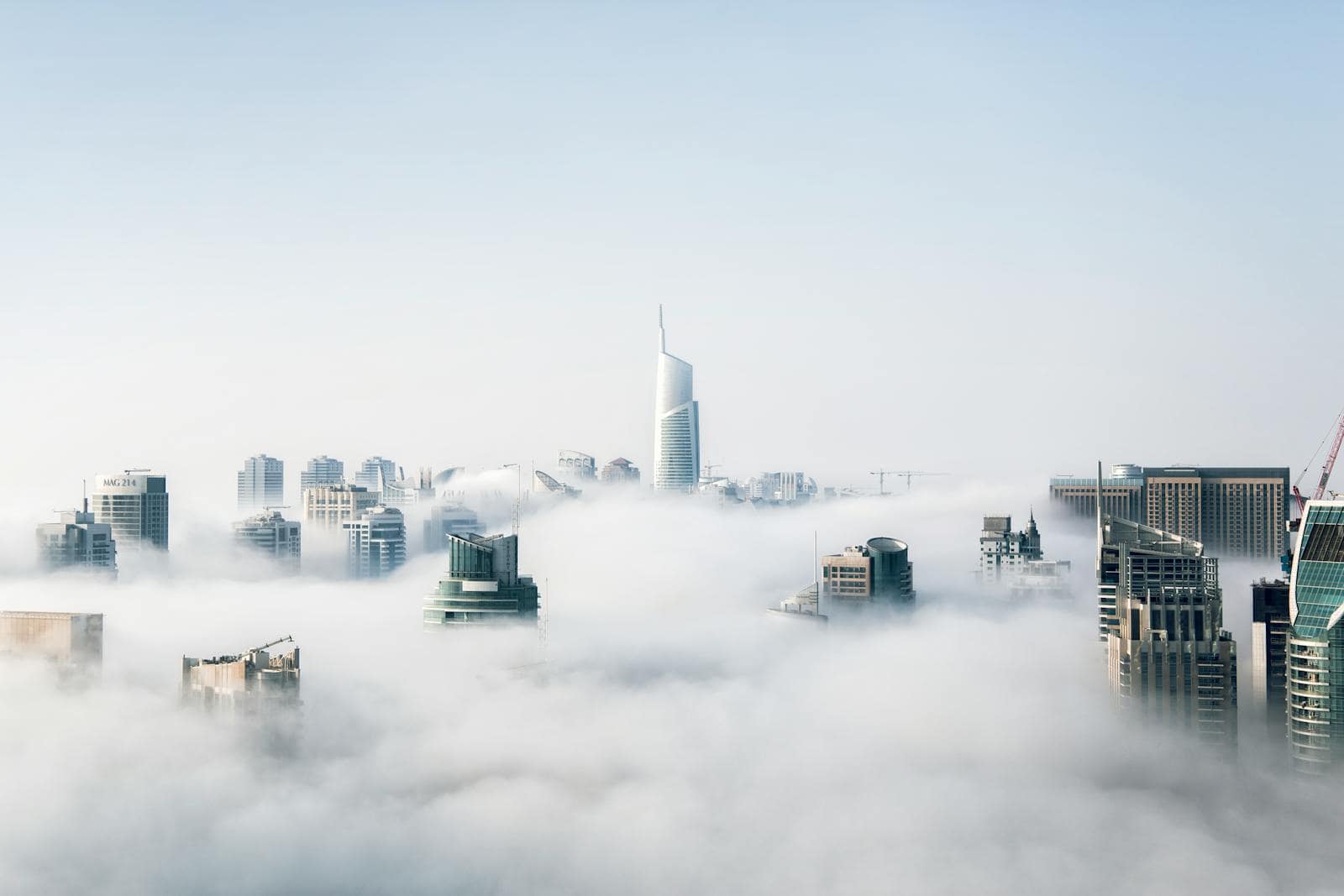 Cloud computing, A stunning view of Dubai skyscrapers emerging through a blanket of fog, showcasing modern architecture.