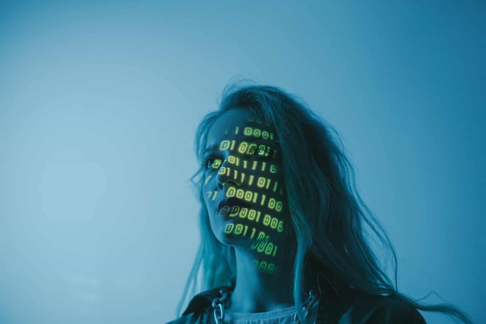 Encryption, Data Security, A woman with binary code lights projected on her face, symbolizing technology.