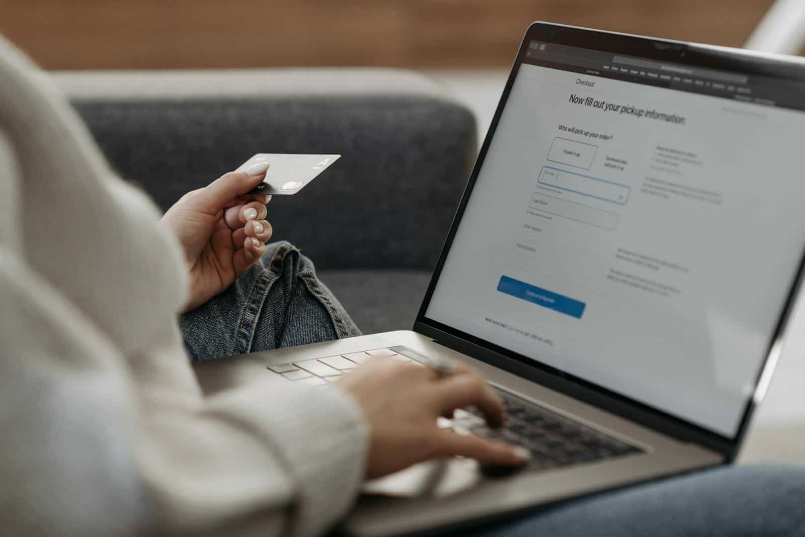 Password Management, Woman holding credit card shopping online on a laptop from a couch.