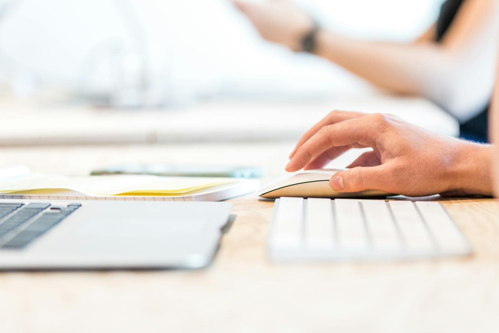 ppc advertising, roi, A person working at a laptop with a wireless mouse and keyboard in a bright office setting.
