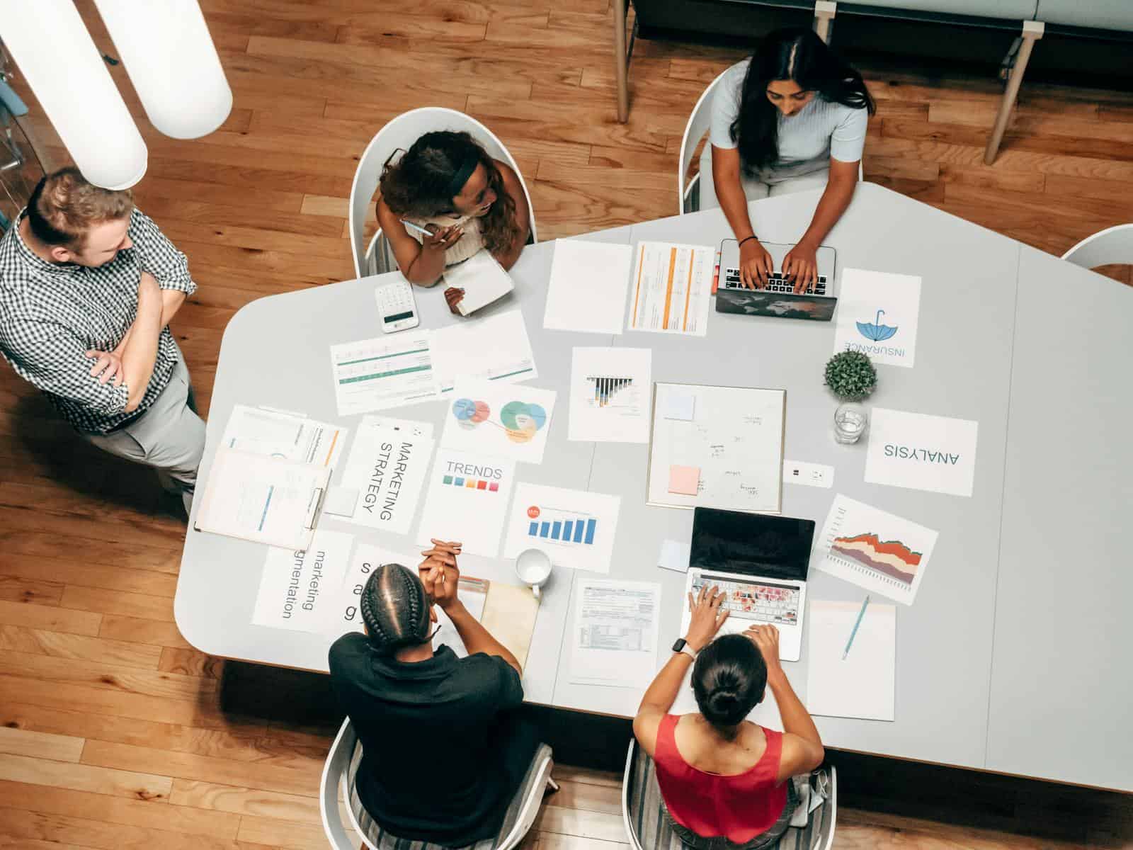 SEO, Google Keyword Planner, A diverse group working on marketing strategies with charts and laptops in an office setting.